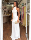 Woman in a white dress standing in a store with racks of clothes in the background