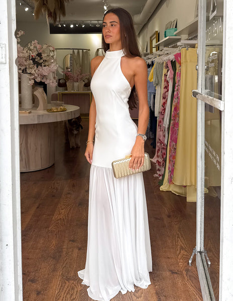 Woman in a white dress standing in a store with racks of clothes in the background